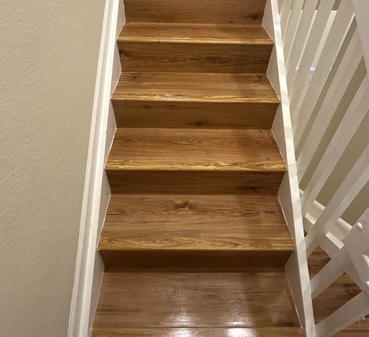 Cleaned wooden staircase with a white painted rail and white risers, seen from the top landing